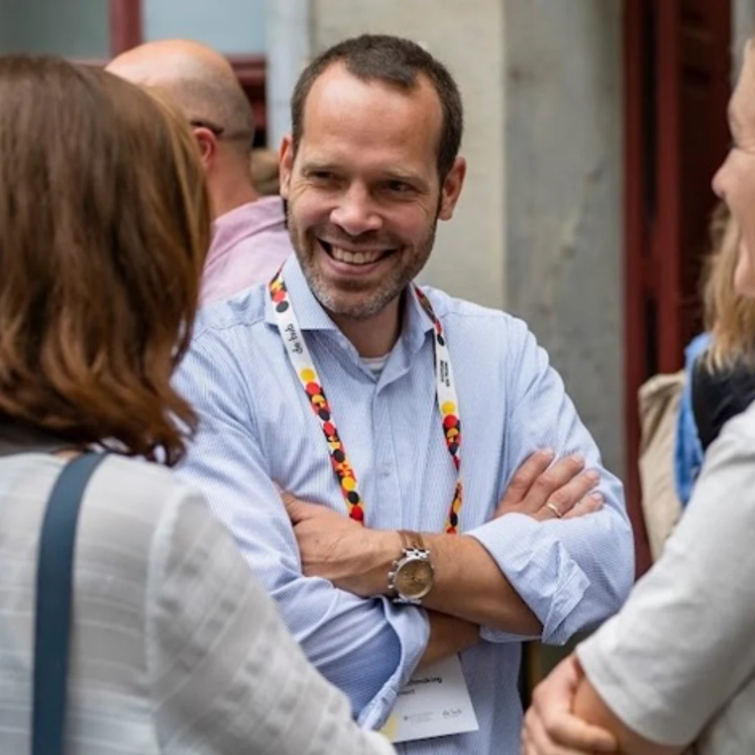 Das Bild zeigt Dennis Ahrens im Gespräch mit zwei Menschen.